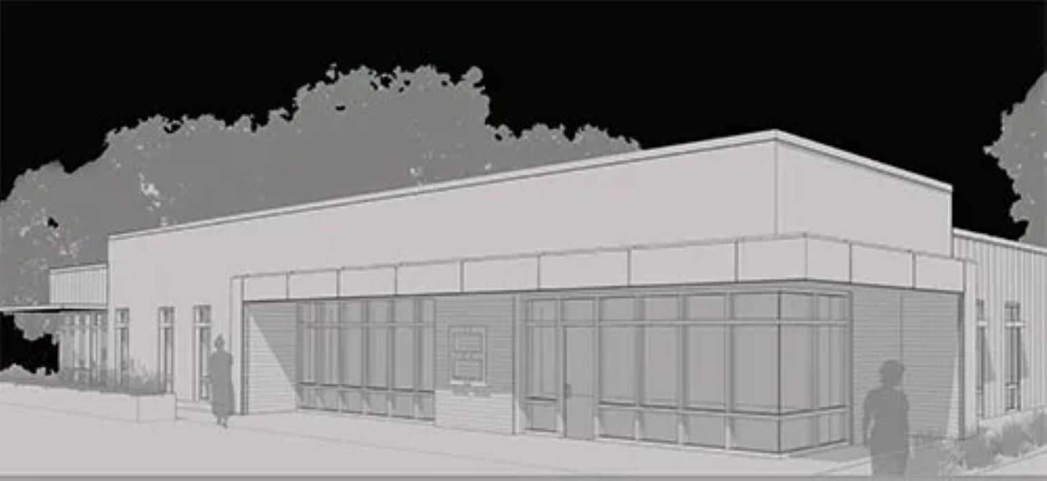 Modern building exterior with large windows and trees in the background.