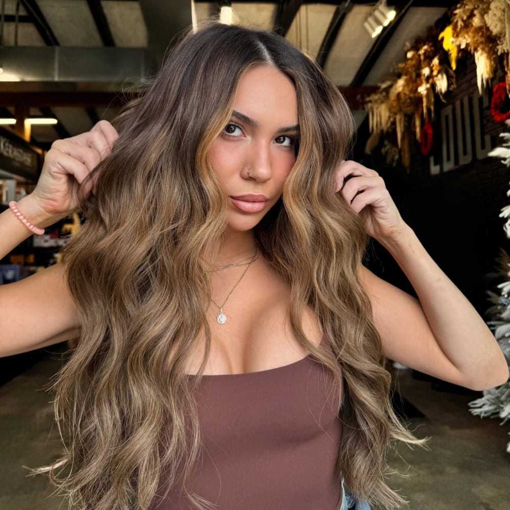 Young woman with long wavy hair in a salon setting.