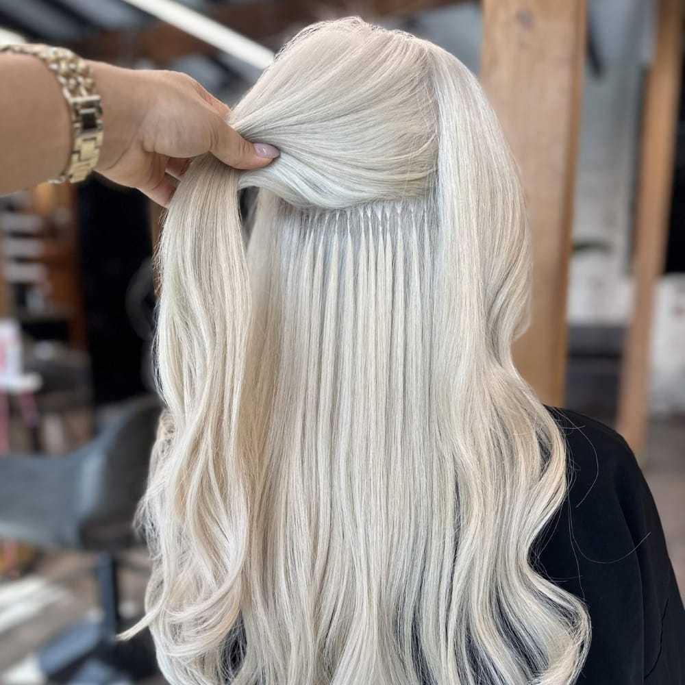 Long platinum blonde hair with extensions being styled in a salon setting.