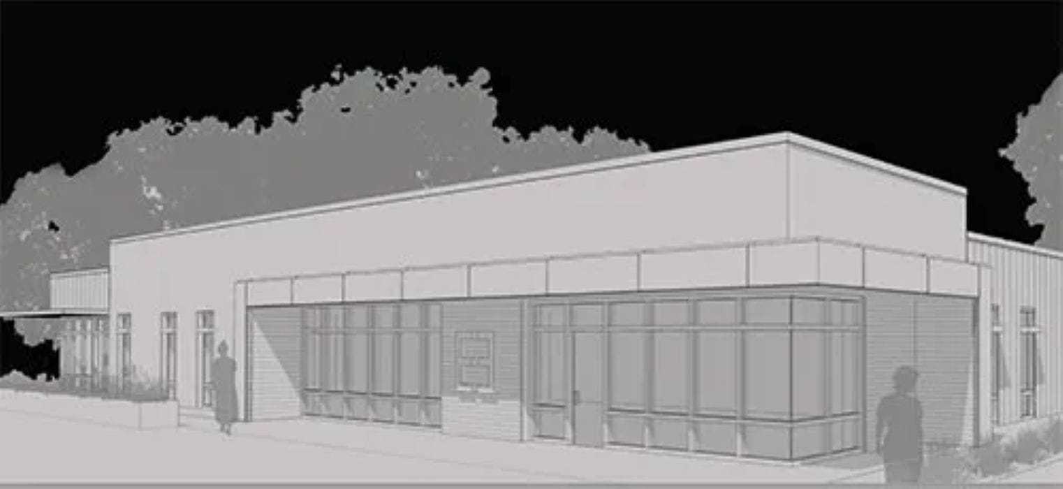 Modern building exterior with large windows and trees in the background.